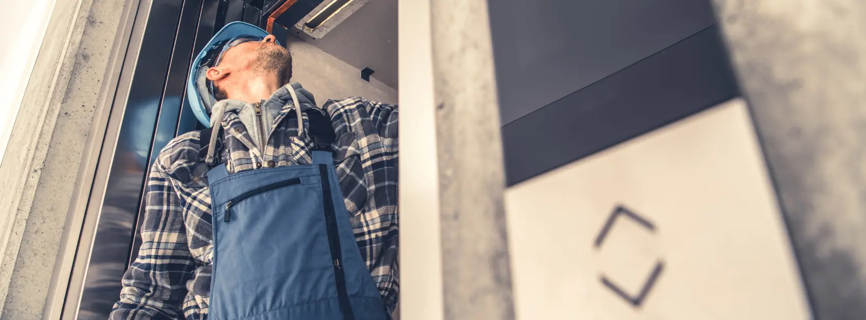 Technicien Tracklift effectuant la maintenance d’un ascenseur avec des pièces d'ascenseur réemploi
