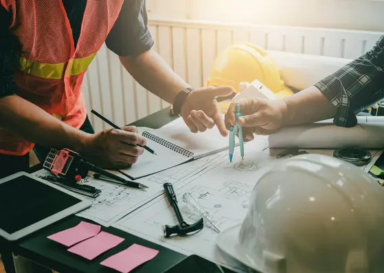 Ingénieurs échangeant sur des plans d’audit PEMD pour le réemploi de pièces d’ascenseur